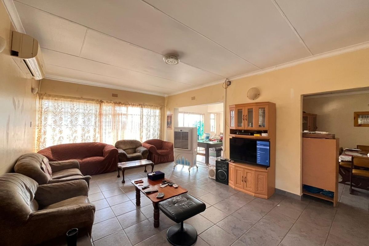 Spacious living room featuring tiled flooring and an integrated air conditioning unit, offering a functional layout with potential for cosmetic updates.