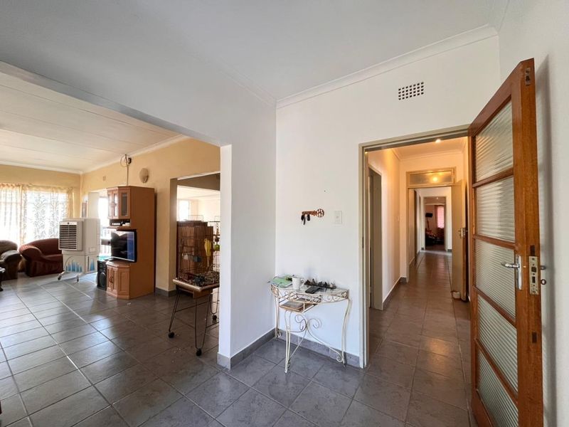 Open plan living area featuring tiled flooring and coved cornicing, providing access to a central hallway and adjacent living space.
