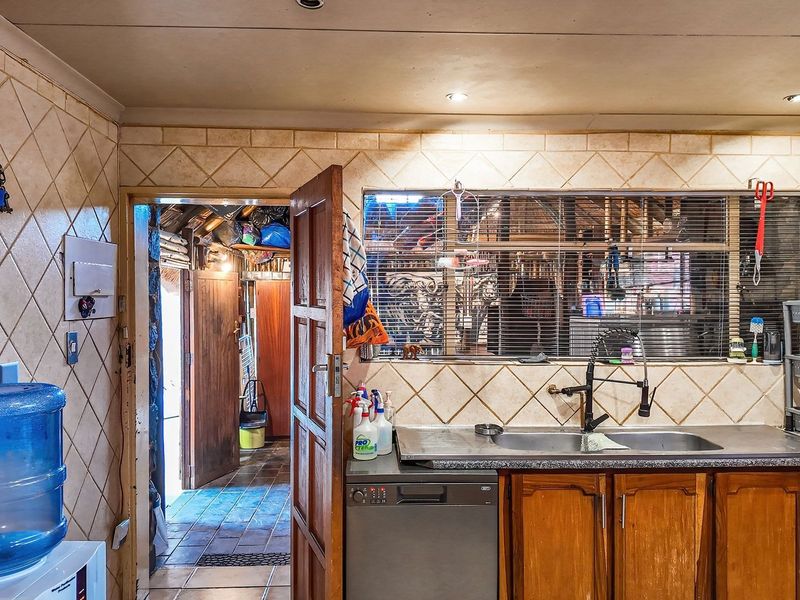 A functional kitchen area featuring a double sink, tiled backsplash, built-in cabinetry, and a wall-mounted solar inverter system.