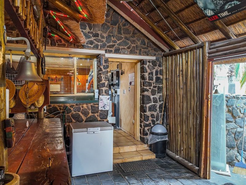 Rustic-style bar area featuring stone wall cladding, a thatched roof, and timber bar counter, providing a unique entertainment space.