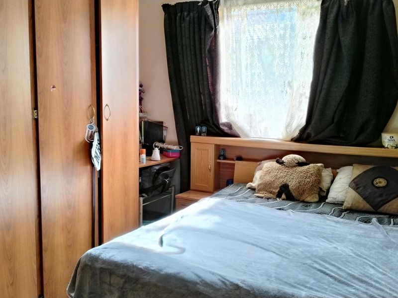 A bedroom featuring a built-in wooden wardrobe and a matching integrated headboard with storage shelving.