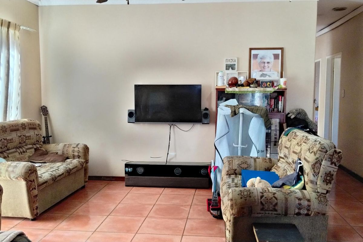 A living room featuring tiled flooring and a wall-mounted television setup.