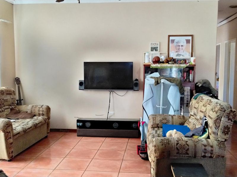 A living room featuring tiled flooring and a wall-mounted television setup.