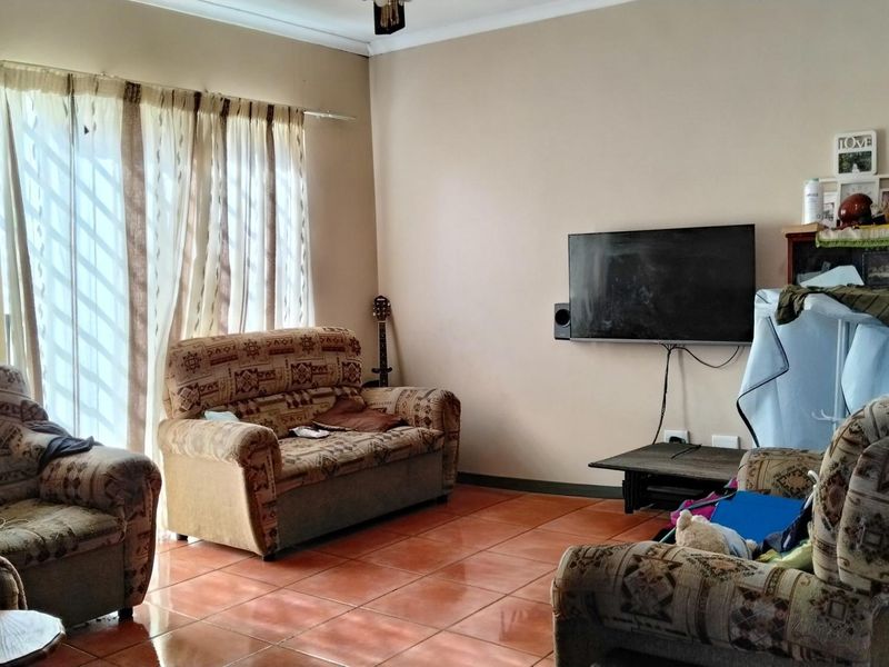 A living room featuring ceramic tile flooring and a wall-mounted television setup, offering a functional space with natural light from the window.