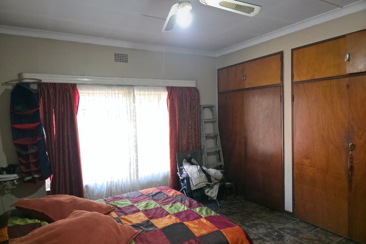 Bedroom featuring built-in wooden cupboards, tiled flooring, and a ceiling fan, offering a functional space with potential for cosmetic updates.