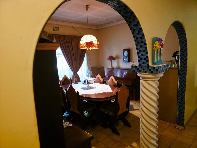 A traditional dining room featuring arched architectural details, a decorative column, and tiled flooring, offering a classic layout with potential for modernization.