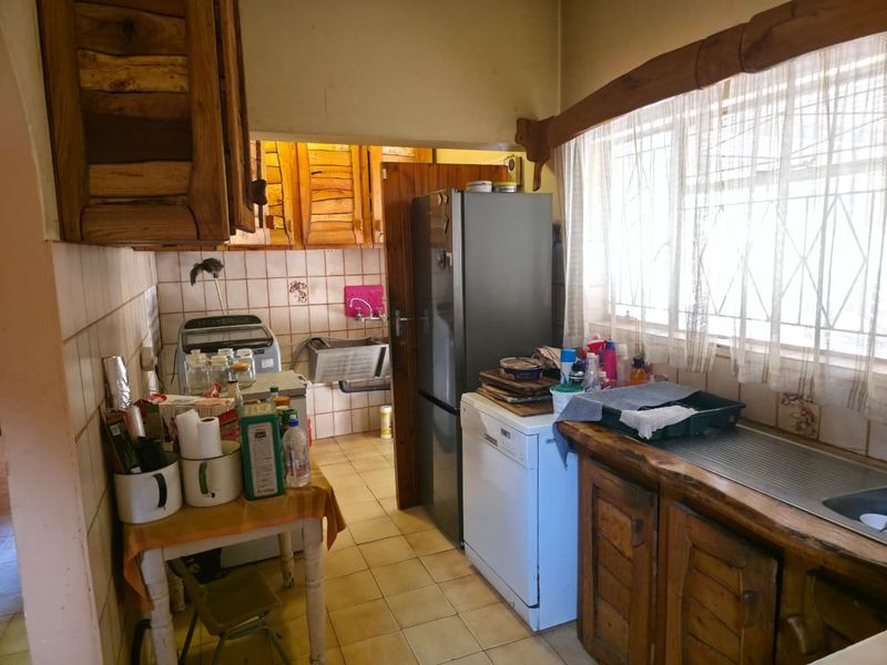 A functional kitchen featuring wooden cabinetry, tiled backsplash, and tiled flooring, offering a dated aesthetic with potential for modernization.