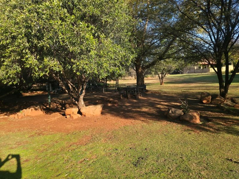 A spacious, naturally landscaped garden area featuring mature trees and large rock formations, providing a serene outdoor setting.