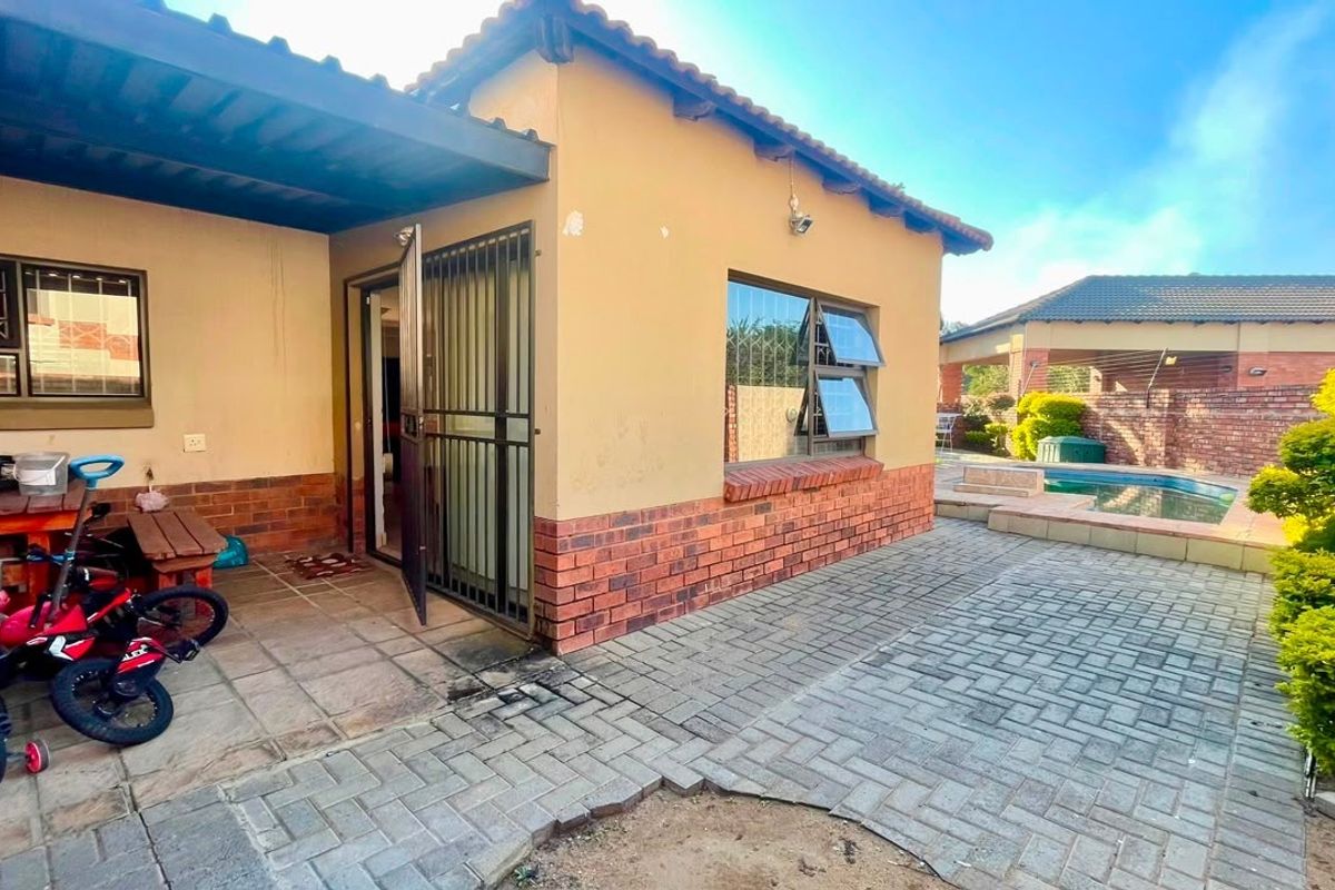 Rear exterior view of the townhouse featuring a paved patio area, security gate, and a private swimming pool in the garden.
