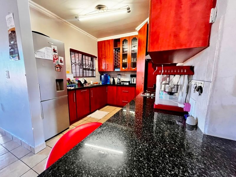 A functional kitchen featuring dark granite countertops, ample wooden cabinetry, and tiled flooring, offering a practical layout for daily meal preparation.
