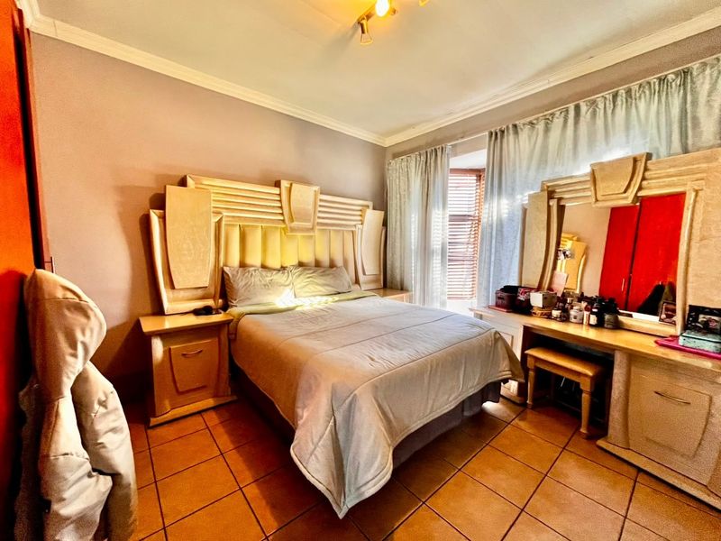 A bedroom featuring tiled flooring, ceiling cornice, and window blinds, providing a functional space with built-in bedroom furniture.