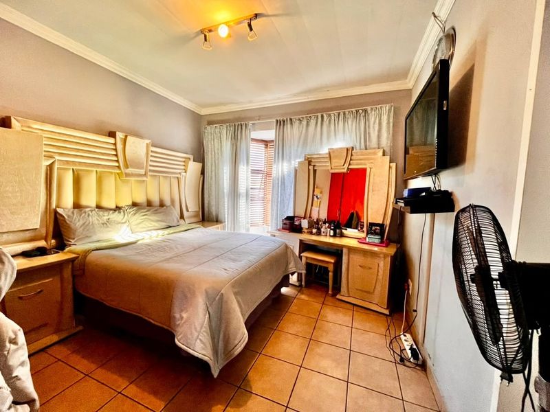 A bedroom featuring tiled flooring, a built-in headboard, and a built-in vanity unit, providing a functional and established sleeping space.