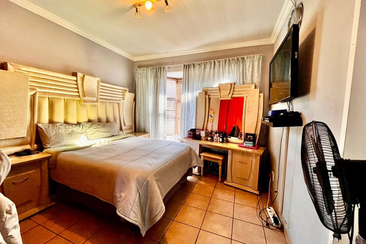 A bedroom featuring tiled flooring, a built-in headboard, and a built-in vanity unit, providing a functional and established sleeping space.