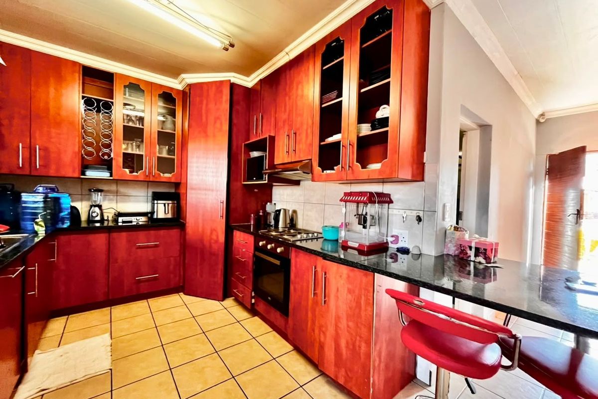 A functional kitchen featuring warm-toned wooden cabinetry, granite countertops, a built-in oven with gas hob, and a convenient breakfast bar area.