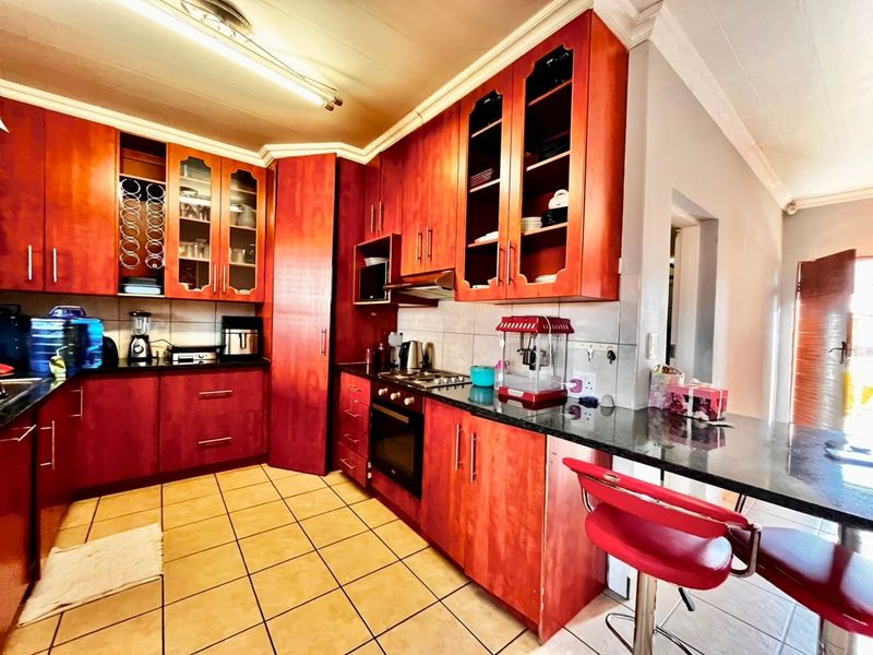 A functional kitchen featuring warm-toned wooden cabinetry, granite countertops, a built-in oven with gas hob, and a convenient breakfast bar area.