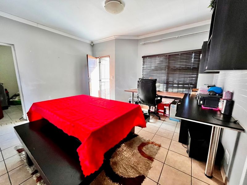 A functional home office space featuring tiled flooring, a built-in desk, and direct access to an exterior security gate.
