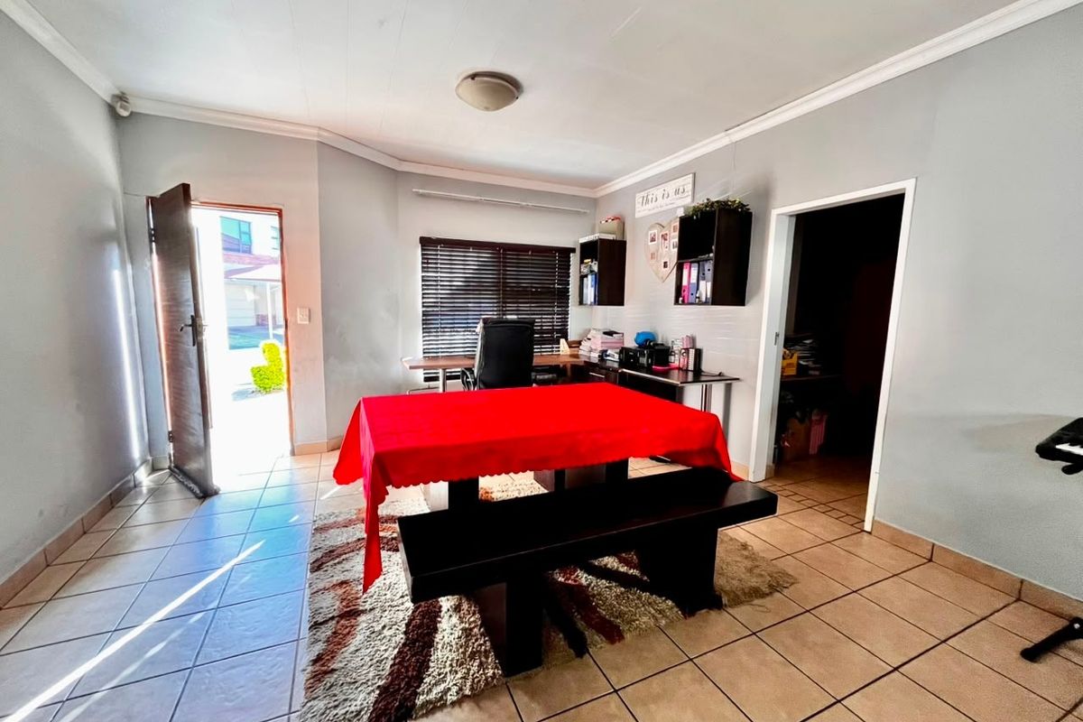 A functional living area featuring tiled flooring, venetian blinds, and direct access to the exterior, offering a versatile space for various uses.