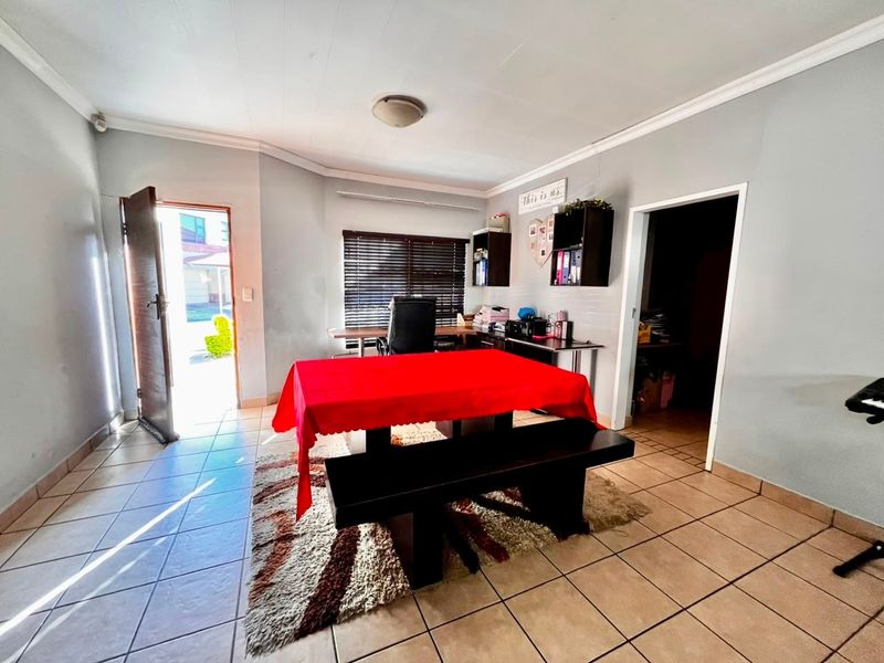 A functional living area featuring tiled flooring, venetian blinds, and direct access to the exterior, offering a versatile space for various uses.