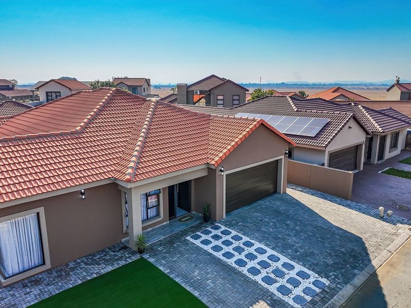 Aerial view of a modern residential property featuring a tiled roof, solar panels, and a paved driveway in a well-maintained estate setting.