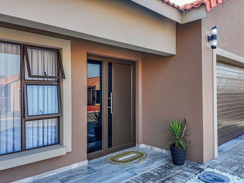 Modern front entrance featuring a paved driveway, double garage, and clean, well-maintained exterior finishes with contemporary aluminium window frames.
