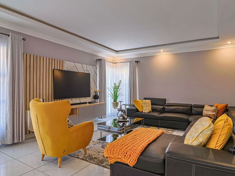 A well-maintained living room featuring tiled flooring, a modern recessed ceiling, and a stylish feature wall with integrated media cabinetry.