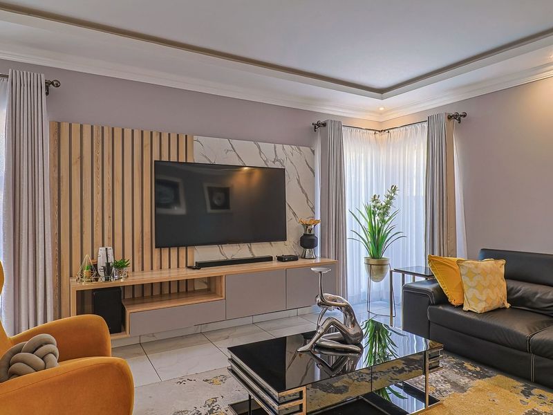 Modern living room featuring a custom built-in media unit with timber slat and marble-effect wall paneling, recessed ceiling lighting, and large windows.