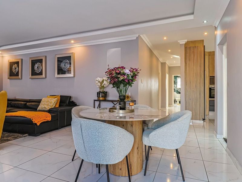 Modern open-plan living and dining area featuring sleek porcelain floor tiles, recessed lighting, and a stylish timber slat feature wall.