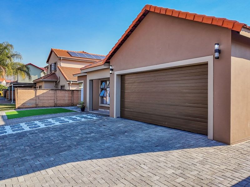Front view of the property featuring a paved driveway, double garage, and well-maintained exterior finishes with a tiled roof.