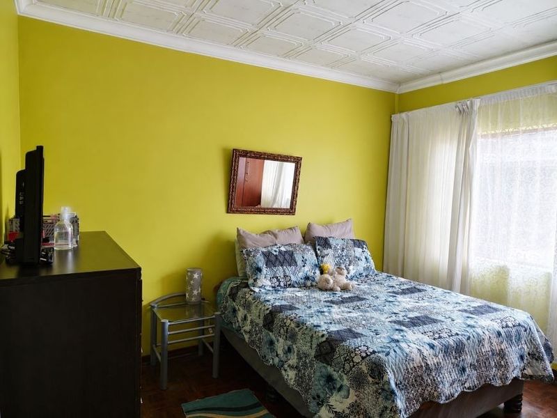 A bedroom featuring parquet flooring and a decorative pressed metal ceiling, offering a classic architectural foundation ready for modern updates.