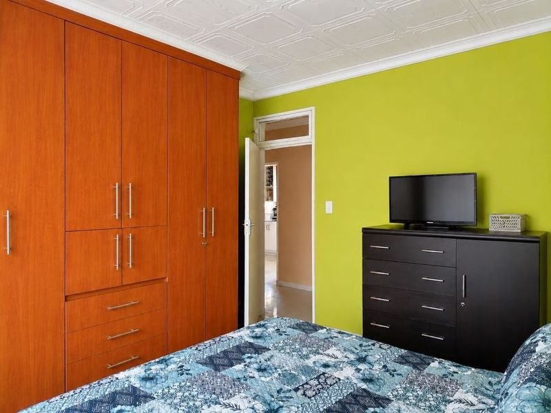 A bedroom featuring a large built-in wooden wardrobe, a decorative coffered ceiling, and a doorway leading to an adjacent room.
