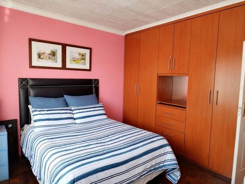 A bedroom featuring built-in wooden cupboards, parquet flooring, and a ceiling with decorative tiles.