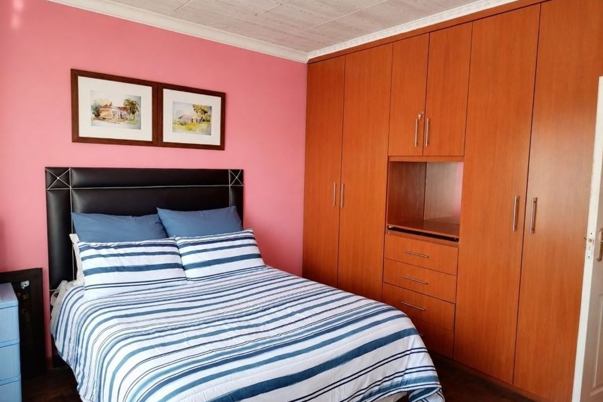 A bedroom featuring built-in wooden cupboards, parquet flooring, and a ceiling with decorative tiles.