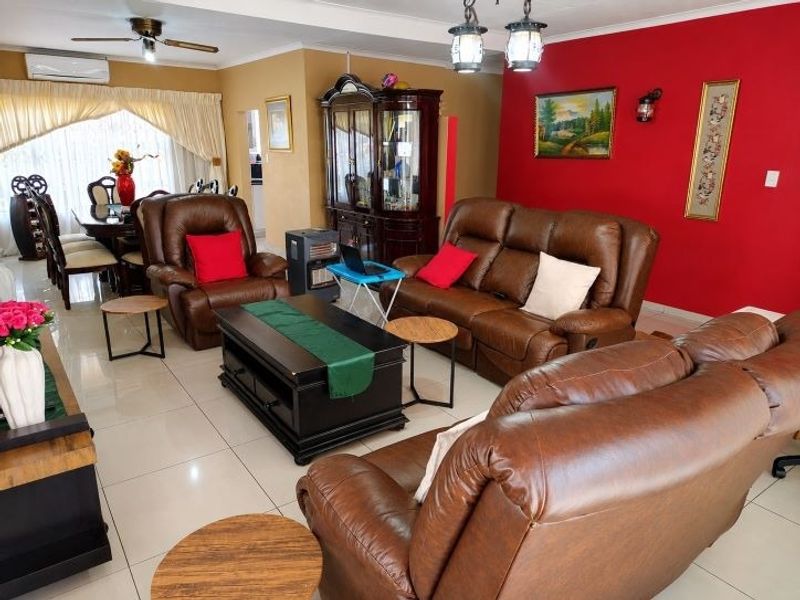 Spacious open-plan living and dining area featuring tiled flooring, a ceiling fan, and a split-system air conditioner for climate control.