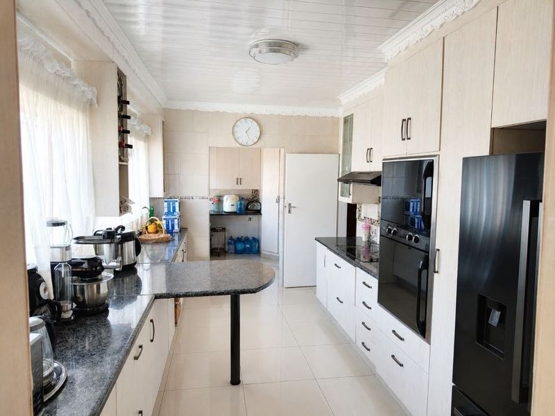 A functional kitchen featuring granite countertops, built-in cabinetry, integrated oven, and a breakfast bar, with tiled flooring and a clean, neutral aesthetic.