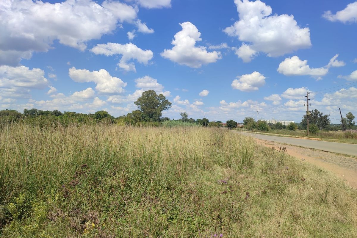A view of the rural landscape featuring a paved road and overhead power lines bordering the open field.