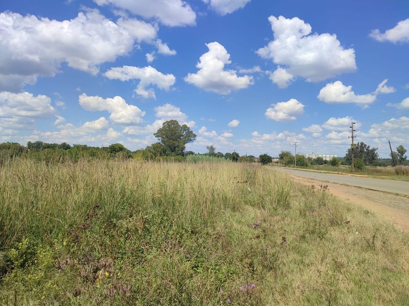 A view of the rural landscape featuring a paved road and overhead power lines bordering the open field.