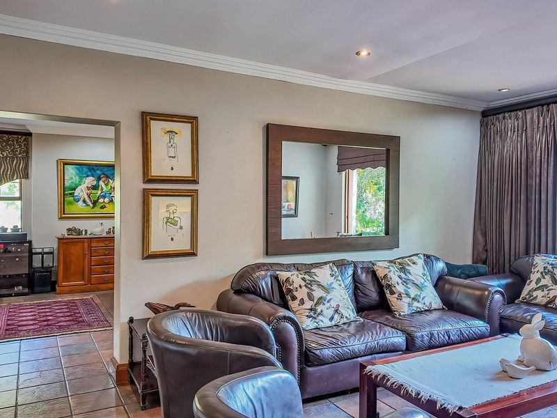 A comfortable living room featuring tiled flooring, crown molding, and recessed lighting, with an open transition into an adjacent room.