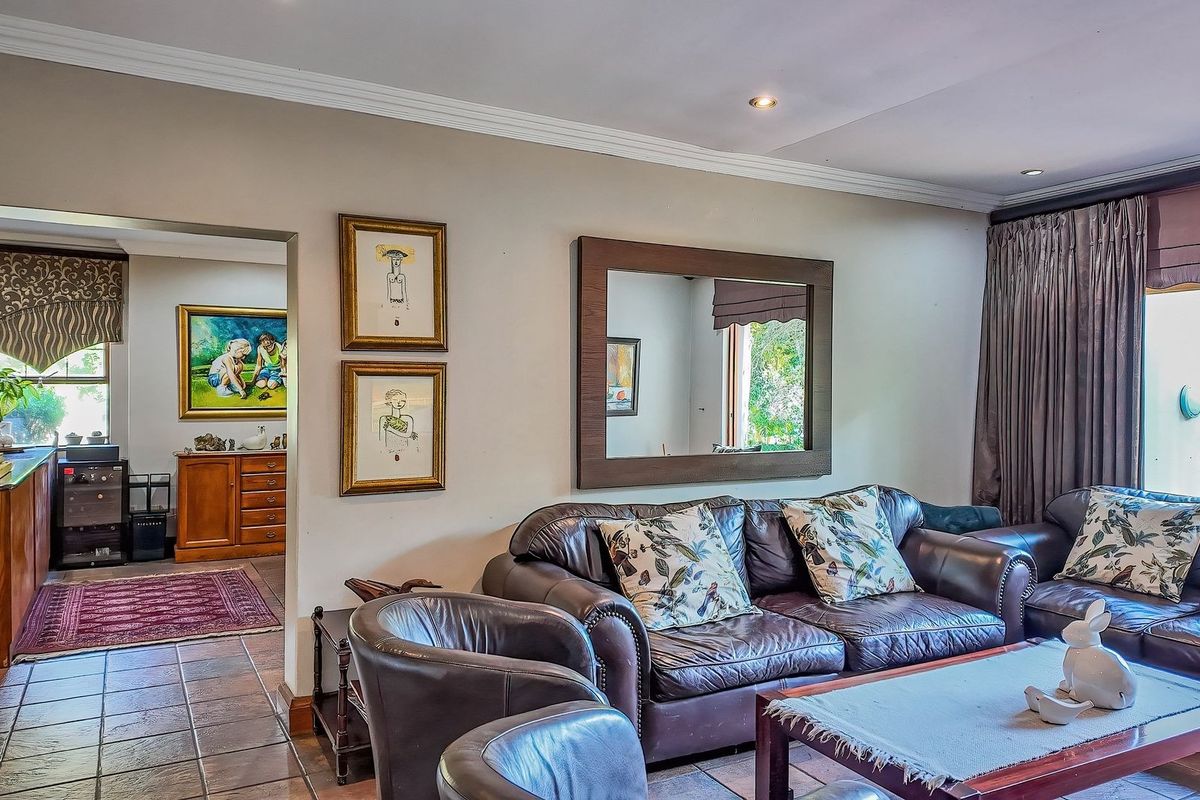A comfortable living room featuring tiled flooring, crown molding, and recessed lighting, with an open transition into an adjacent room.
