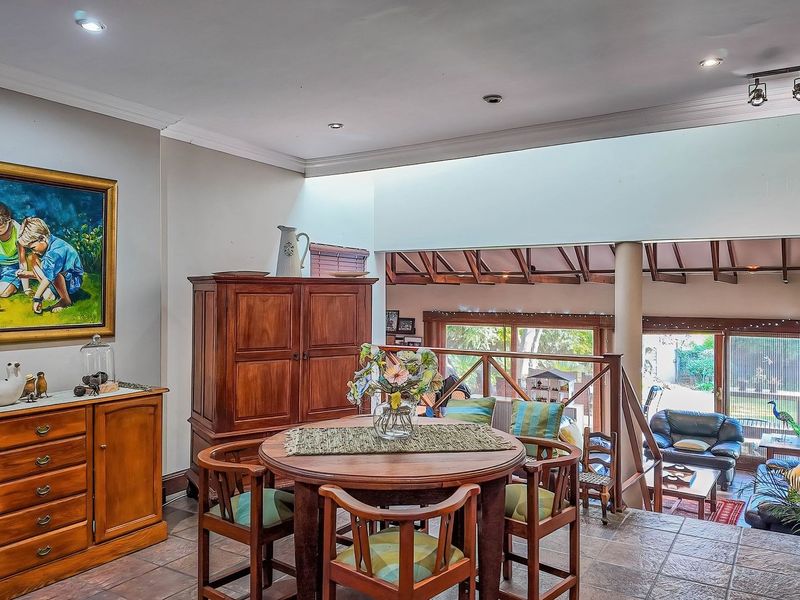 Open-plan living area featuring tiled flooring, a skylight, and a split-level layout with a wooden staircase railing overlooking the lower lounge space.