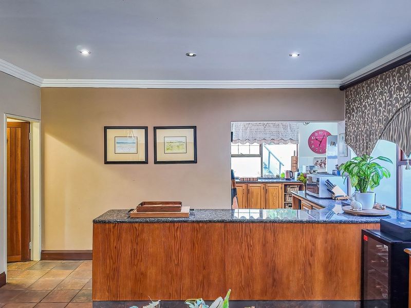 Open plan kitchen area featuring a granite breakfast bar, wooden cabinetry, and tiled flooring with recessed lighting and crown molding details.