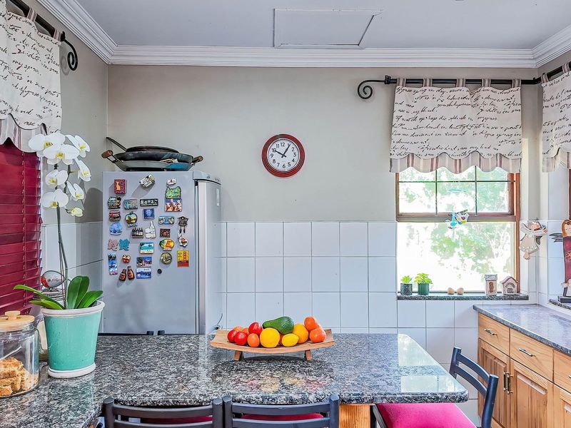 A functional kitchen featuring granite countertops, tiled backsplash, and warm-toned wooden cabinetry with natural light from multiple windows.