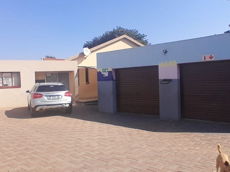 Front view of the property featuring a paved driveway and a double garage with roller shutter doors.