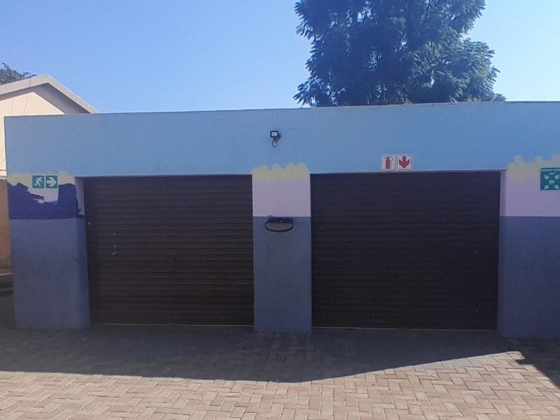A detached double garage featuring two roller doors and a paved driveway, showing signs of weathered exterior paint.