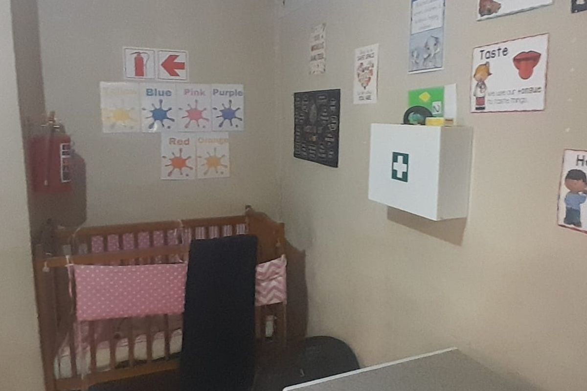 A small bedroom space currently utilized with educational wall decor, featuring a wall-mounted first aid cabinet and fire safety equipment.