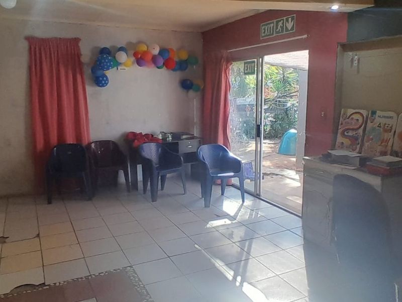 A living area featuring tiled flooring and a sliding glass door leading to the exterior, currently showing signs of wear and damaged floor tiles.