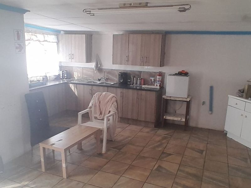 A functional kitchen area featuring laminate cabinetry, tiled flooring, and a stainless steel sink, offering potential for modernization and layout optimization.