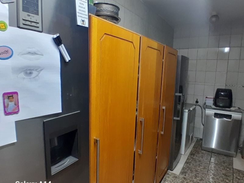 A functional scullery area featuring tiled walls, tiled flooring, and built-in cabinetry providing additional storage and utility space.