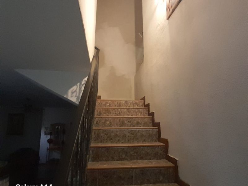 A staircase featuring tiled steps and a metal balustrade, showing signs of unfinished wall plastering and requiring cosmetic attention.