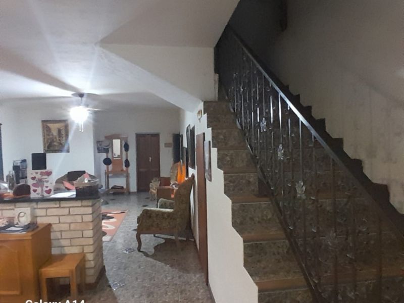 Open plan living area featuring a staircase with wrought iron balustrade, tiled flooring, and a brick breakfast bar.