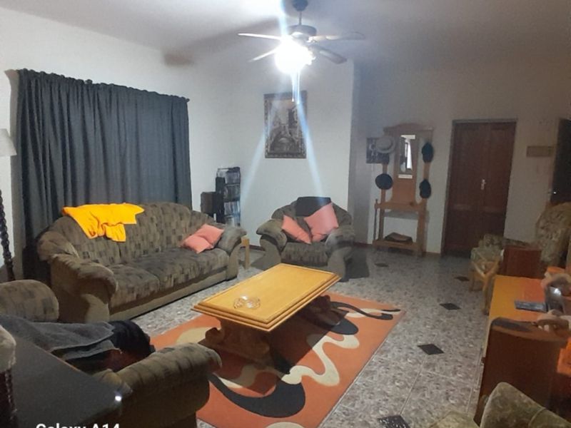 A spacious living room featuring tiled flooring and a central ceiling fan, providing a functional and comfortable area for relaxation.